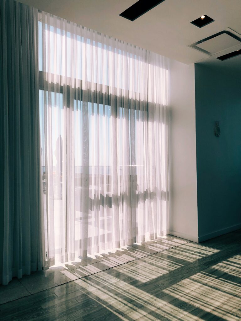 A floor to ceiling window with light curtains